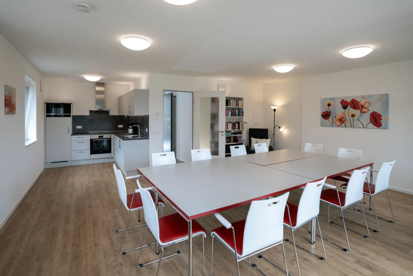 Heller Gemeinschaftsraum mit großer Tafel und Küchenzeile